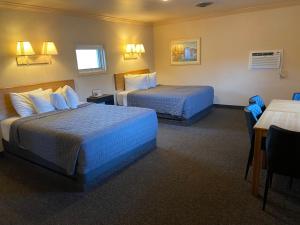 a hotel room with two beds and two tables at Woodland Motel in Salida