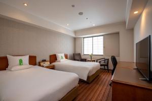 um quarto de hotel com duas camas e uma televisão de ecrã plano em International Garden Hotel Narita em Narita