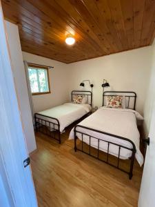 Habitación pequeña con 2 camas y techos de madera. en The Finch Beach Resort en North Bay