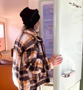 Uma mulher está a olhar para um frigorífico aberto. em The Finch Beach Resort em North Bay
