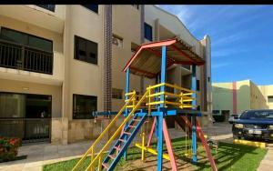 um colorido parque infantil em frente a um edifício em Crystal Park Flat em Aquiraz