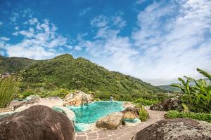 a swimming pool with rocks and mountains in the background at Coffee Pickers Village By Hacienda Orosi in Cartago