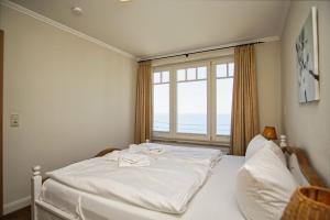 Cama blanca en habitación con ventana en Ferienwohnung mit traumhaftem Meerblick - Haus am Meer FeWo 07, en Lohme