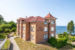 a large brick building with the ocean in the background at Ferienwohnung mit traumhaftem Meerblick - Haus am Meer FeWo 07 in Lohme