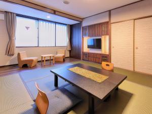 una camera con tavolo, sedie e televisore di Gion Shinmonso a Kyoto