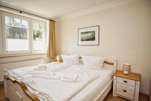 białe łóżko w sypialni z oknem w obiekcie Ferienwohnung mit traumhaftem Meerblick - Haus am Meer FeWo 01 w mieście Lohme