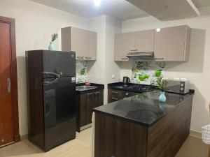 a kitchen with a black refrigerator and wooden cabinets at ازها العين السخنه in Ain Sokhna