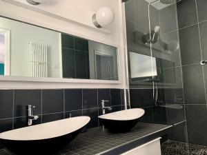 La salle de bains est pourvue de 2 lavabos, d'une baignoire et d'un miroir. dans l'établissement Villa Hyper Centre, à Arcachon