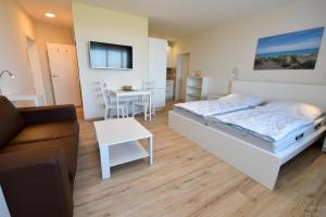 a bedroom with a bed and a couch and a table at Haus "Atlantic" Appartement ATL 604B in Cuxhaven +17 photos