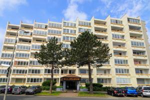 a large white building with cars parked in a parking lot at Haus "Atlantic" Appartement ATL 604B in Cuxhaven