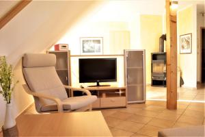 een woonkamer met een stoel en een televisie bij Roter Erik App 3, DG li in Kirchdorf