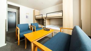 福岡市にあるALPHABED INN 福岡大濠公園の椅子、テーブル、二段ベッドが備わる客室です。