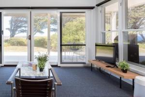 a living room with a tv and a table and windows at Ventnor Cosy Homestead in Ventnor