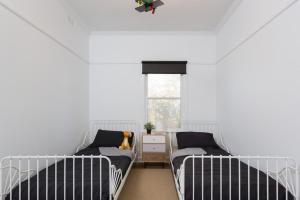 two beds in a white room with a window at Ventnor Cosy Homestead in Ventnor