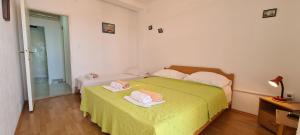 a bedroom with a green bed with two towels on it at Apartments Ana i Ante Punta in Milna