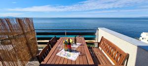 a balcony with a table with wine bottles and glasses at Apartments Ana i Ante Punta in Milna
