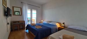 a hotel room with two beds and a window at Apartments Ana i Ante Punta in Milna