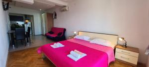 a bedroom with a pink bed with two towels on it at Apartments Ana i Ante Punta in Milna