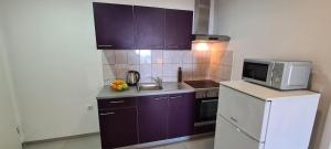 a small kitchen with purple cabinets and a microwave at Apartments Ana i Ante Punta in Milna