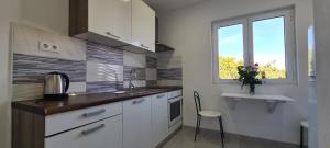 a kitchen with white cabinets and a sink and a window at Apartments Ana i Ante Punta in Milna
