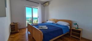 a bedroom with a bed with a blue blanket and a window at Apartments Ana i Ante Punta in Milna