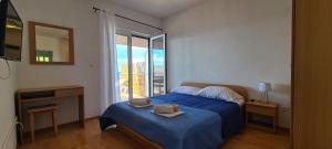 a bedroom with a bed with a blue blanket and a window at Apartments Ana i Ante Punta in Milna