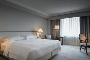 高雄市にあるグランド ハイ ライ ホテルの白い大型ベッドと椅子が備わるホテルルームです。