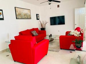 sala de estar con 2 sillas rojas y TV en Homecancun en Cancún