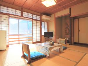 sala de estar con mesa, sillas y TV en Ougiya Ryokan, en Toyooka