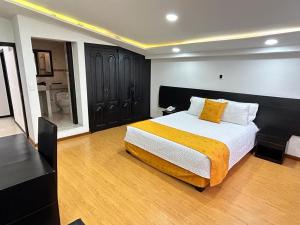 a bedroom with a large bed with a yellow blanket at Hotel Lagos Latin America in Pasto