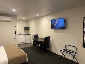 a room with a bed and a table and a tv on the wall at Riverlea Motel in Gore