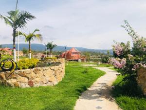 a stone wall and a path with trees and flowers at Glamping Sierra de Luna in Villa de Leyva