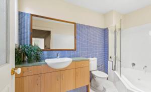 a bathroom with a sink and a toilet and a mirror at Intermission at Queenscliff in Queenscliff