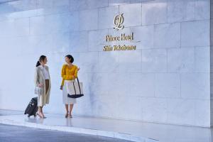 Shin Yokohama Prince Hotel في يوكوهاما: سيدتان واقفتان أمام جدار أبيض