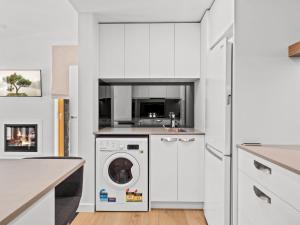 a white kitchen with a washing machine in it at Yuki Studio in Crackenback