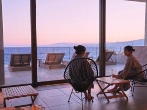 two women sitting in chairs looking out at the ocean at Oiso Prince Hotel in Oiso