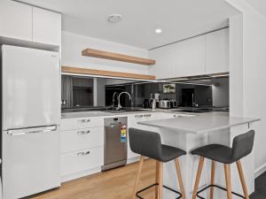 a kitchen with white cabinets and a table and two chairs at Yuki Studio in Crackenback