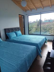 Dos camas en una habitación con una gran ventana. en Apartamento La bonita guatape, en Guatapé