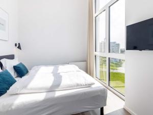 a white bedroom with a bed and a large window at Apartment Wendtorf XXIX in Wendtorf