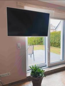 een grote flatscreen-tv op een raam met een plant bij "Casa Diego"Ferienhaus mit Garten in Bielefeld