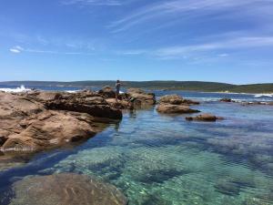 a person standing on some rocks in the water at Panda's Patch Dunsborough in Dunsborough