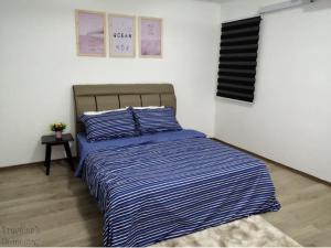 un letto con piumone a righe blu e bianche in una camera da letto di [FREE WI-FI]Travelers Homestay Sitiawan[6~10Pax]The Venus Apartment a Sitiawan