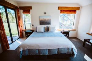 a bedroom with a large bed with two windows at The River House Wanaka in Wanaka