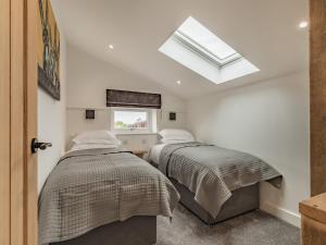 two beds in a bedroom with a skylight at The Old Haybarn in Longford