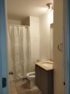 y baño con aseo y cortina de ducha. en Departamento 1 Dormitorio 1 Baño Valparaíso, en Valparaíso