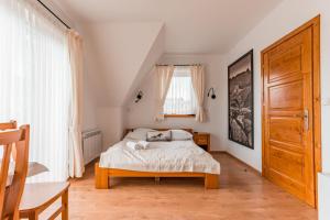 a bedroom with a bed and a wooden door at Willa Siuster - komfortowa willa z widokiem na góry i doskonałą lokalizacją - niedaleko Term Bukovina in Bukowina Tatrzańska