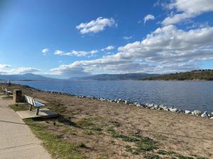 a bench sitting next to a body of water at Jindabyne Lake View in Jindabyne