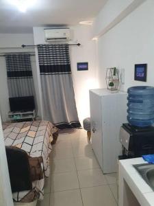 Apartemen 1 BR Studio Baywalk Pluit Cozy Aesthetic North Jakarta في جاكرتا: غرفة صغيرة فيها سرير وثلاجة