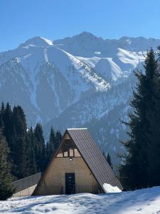 a barn in the snow with mountains in the background at Super View-2 Bedroom Chalet Karakol in Karakol