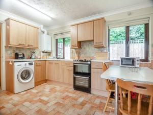 uma cozinha com armários de madeira e uma mesa com cadeiras em Clover Cottage - W40835 em Horsford